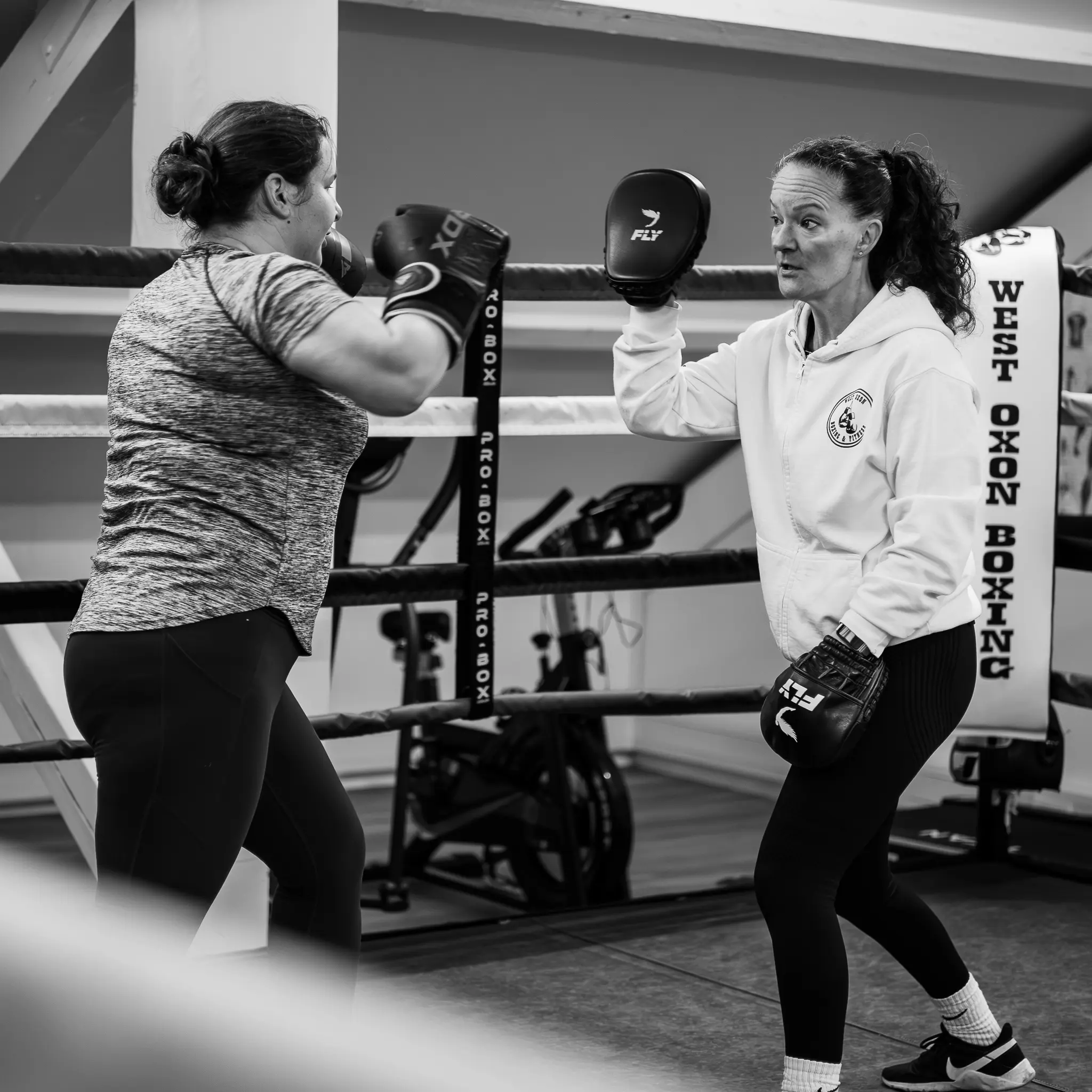 Women's Precision Pad Work Witney An instructor holding focus mitts for a female student practicing precise hooks and jabs in the West Oxon Boxing ring.